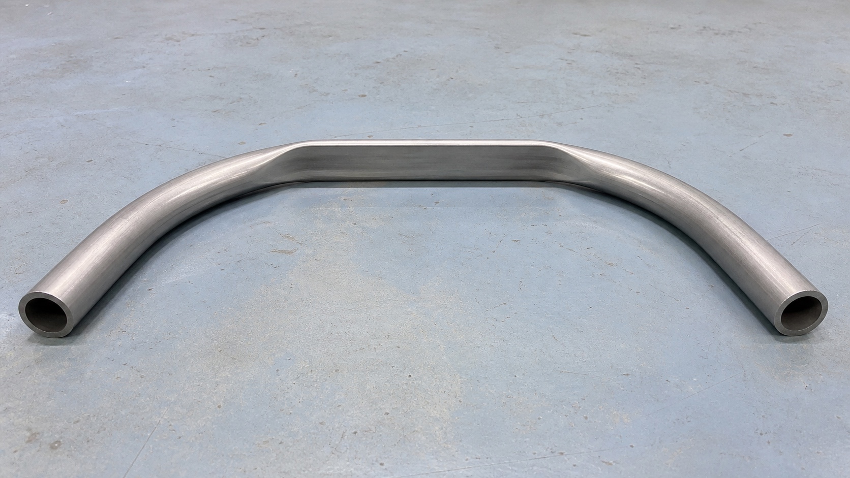 Photorealistic engineering concept of a continuous thin-walled metal tube transitioning from round end sections into a non-round formed center section